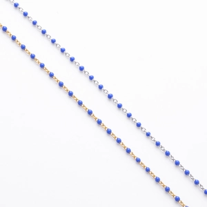 Close-up of minimalist gold and silver chains with vibrant blue enamel bead accents