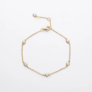 Detail of minimalist gold chain bracelet featuring five bezel-set round clear zircons