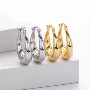 Boucles d'oreilles gouttes polies en argent et or présentées sur des blocs géométriques
