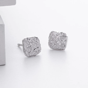 Macro-opname van S925 sterling zilveren vierkante oorknopjes met onregelmatige lavatextuur