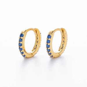 Detail of gold huggie hoop earrings with micro-paved blue round cubic zirconia stones