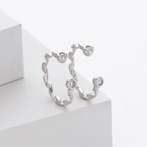 Macro detail of S925 sterling silver ribbon twist earrings with sparkling zircon stones