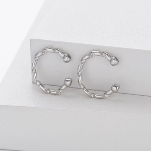 Macro detail of S925 sterling silver ear cuffs with twisted ribbon design on white stand
