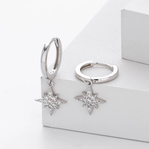 Macro detail of S925 sterling silver hoop earrings with shimmering star charm and zircon