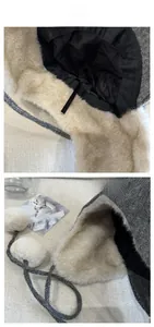 Close-up of winter grey plaid trapper hat with warm faux fur lining and white pom-poms