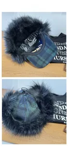Detail of blue-green plaid trapper hat with black faux fur lining and top tie straps