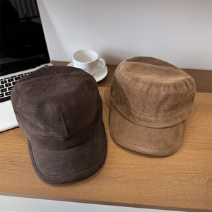 Women suede flat top newsboy hat in brown and beige colors on a desk setup