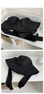 Detail of black cotton bucket hat with wide long ties and white polka dot embroidery