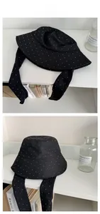 Detail of black breathable sun hat with white polka dots and stylish long ribbon ties