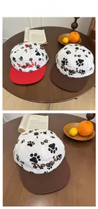 Close-up of baseball caps with paw prints and letter embroidery on a cozy wooden table