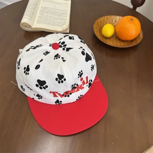 Puppy paw print baseball cap with red contrast brim and Toekil embroidery on a wooden table