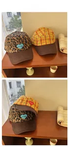 Detail view of heart embroidery and corduroy brim on plaid and leopard baseball caps