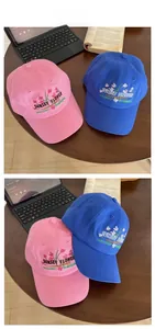 Detailed floral embroidery on cotton baseball caps in pink and blue on a wooden table