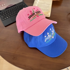 Pink and blue baseball caps with flower embroidery on a wooden table, casual lifestyle