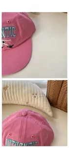 Detail of pink cotton baseball cap featuring light blue 3D embroidered Authentic letters