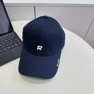 Deep blue baseball cap with 3D white R embroidery on a minimalist white desk setting