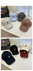 Collection of cotton baseball caps with H embroidery shown in multiple colors on a desk