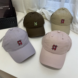 Trendy cotton baseball caps with H embroidery in four colors on a clean white table