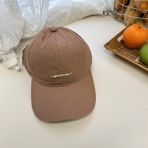 Brown cotton baseball cap with sheenlines embroidery shown in a cozy home setting