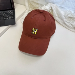 Fashionable brick red baseball cap with H embroidery and cat motif on white table