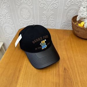 Two-tone baseball cap with bear embroidery and curved brim on wooden desk