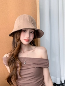 Detail of checkered edge lining on a beige cotton-linen sun hat worn by a model
