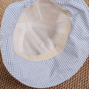 Detail view of baby sun hat showing blue plaid fabric and breathable white mesh lining