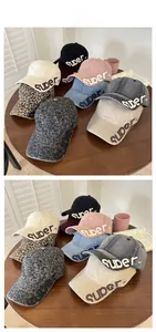 Various distressed baseball caps with embroidered letters displayed on a wooden table