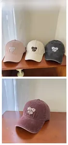 Detail view of cotton baseball caps in pink, beige, and black with letter embroidery