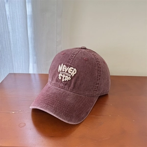 Vintage burgundy washed cotton baseball cap with white letter embroidery on wooden table