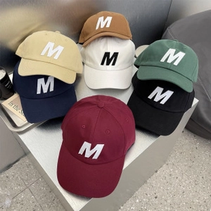 Detailed view of assorted cotton baseball caps with 3D M letter embroidery on front