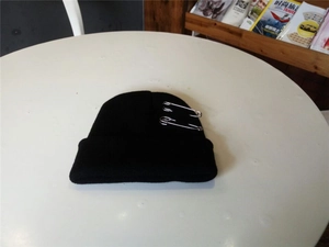 Detail van zwarte gebreide muts met twee zilverkleurige metalen veiligheidsspelden