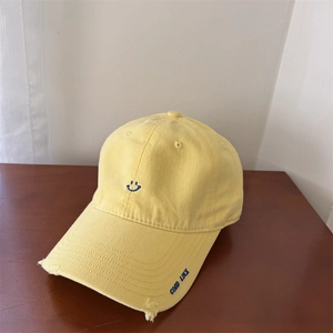 Yellow cotton baseball cap with blue smiley face embroidery and distressed brim details