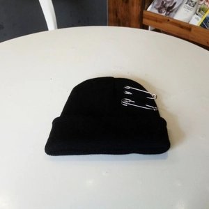 Zwarte gebreide beanie in streetwear-stijl met decoratieve zilveren veiligheidsspelden