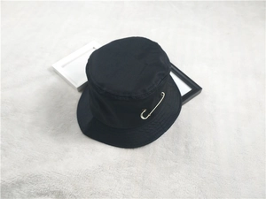 Détail d'un bob en coton noir orné d'une épingle de sûreté dorée décorative élégante