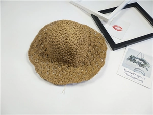 Dettaglio cappello di paglia marrone con bordi smerlati e motivi traforati fatti a mano