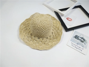 Dettaglio della tesa in pizzo traforato su un cappello di paglia beige per la spiaggia