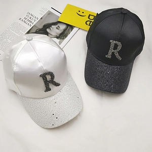 Detailed view of satin baseball caps with rhinestone R logo and glittered brims