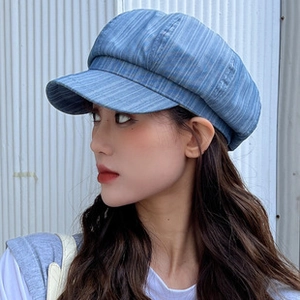Detailed side view of a blue striped newsboy cap made of washed denim fabric