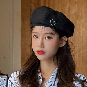 Close-up of black beret featuring a white embroidered heart on cotton blend fabric
