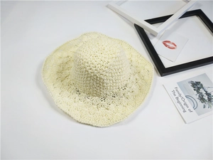 Dettaglio cappello di paglia beige con motivi traforati a ventaglio e bordo ondulato