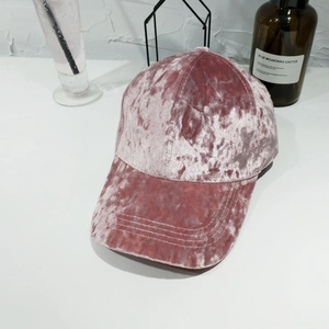 Dettaglio del cappello da baseball in velluto rosa con trama setosa e cuciture fini
