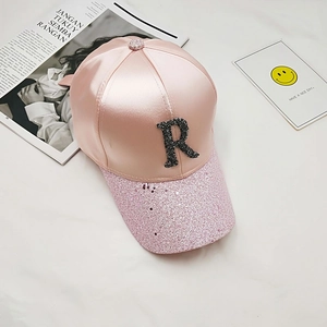 Detail of light pink satin baseball cap with sparkling sequins and black crystal R letter
