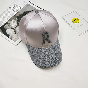 Detailed top view of champagne satin baseball cap with rhinestone R and glitter brim