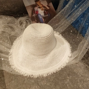 Detail shot of white woven straw hat with frayed edges on aesthetic background