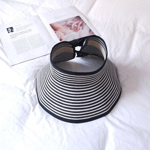 Detailed top view of black and white striped sun hat with wide brim on white fabric