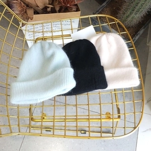 Close-up of thick ribbed knit beanies in blue, black, and beige with soft fuzzy texture