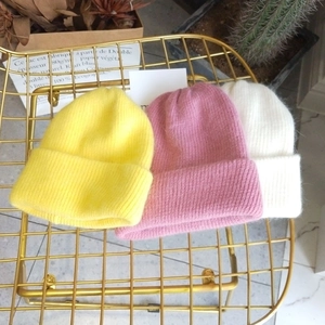Detailed knit texture of thick angora rabbit fur hats in yellow, pink, and white