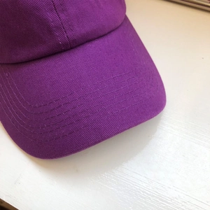 Dettaglio della visiera del cappellino da baseball viola con cuciture di rinforzo