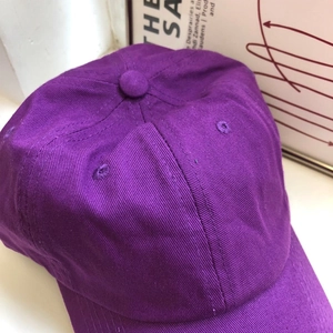 Dettaglio di un cappellino in twill di cotone viola con visiera curva e occhielli
